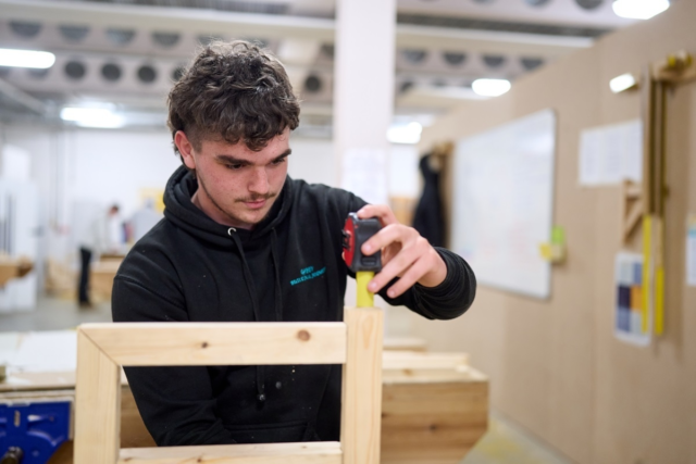 Carpentry student measuring a wooden frame