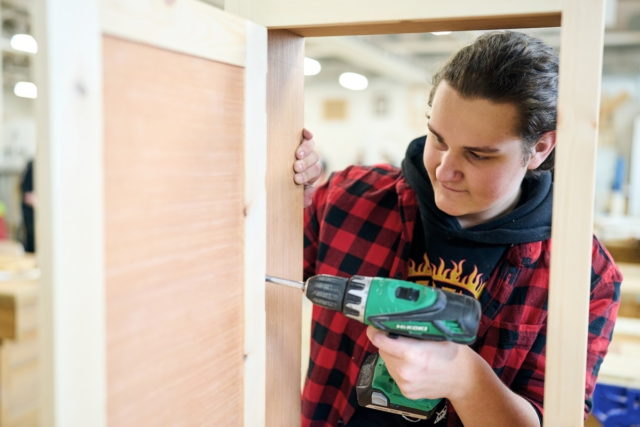 Carpentry student drilling a wooden frame