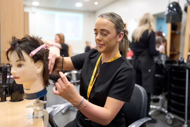Hairdressing student practising on a mannequin head