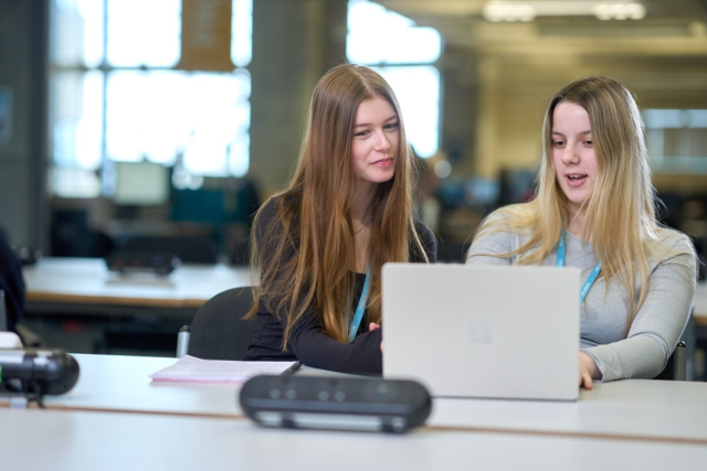 Two students discussing work on a laptop screen in the Learning Centre