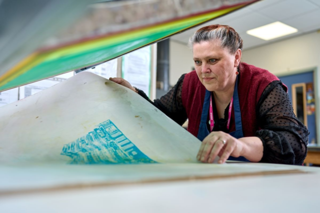 A student prints a design on a printing press Graphics