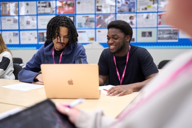 Two Business students work on a laptop