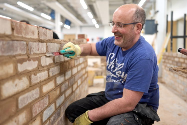 A student builds a brick wall