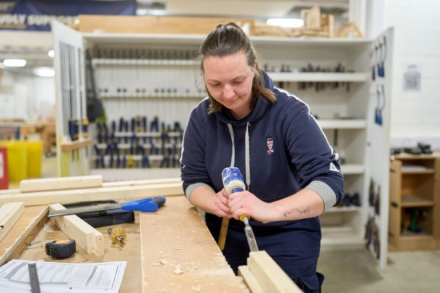 A student uses a chisel