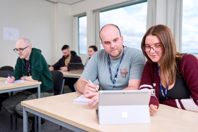 Access Health two students look at a laptop and discuss work