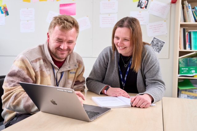 Two students smile at a laptop Childrens Development