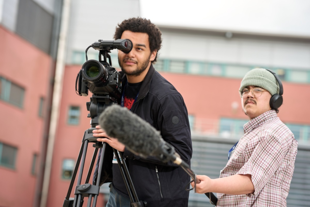 One student films while another holds a microphone Film