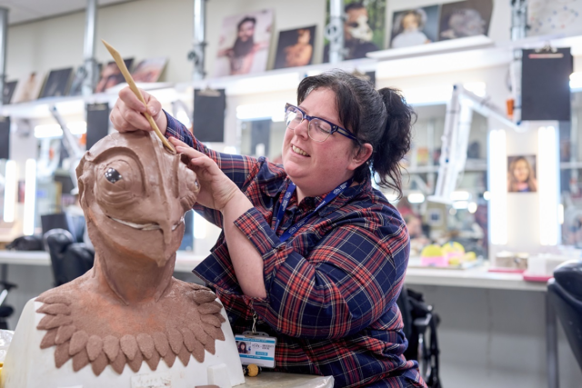 A student mould a prosthetic mask on a bust Media Makeup