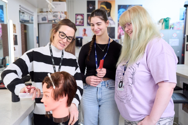 A tutor demonstrates wig techniques to two students Media Makeup