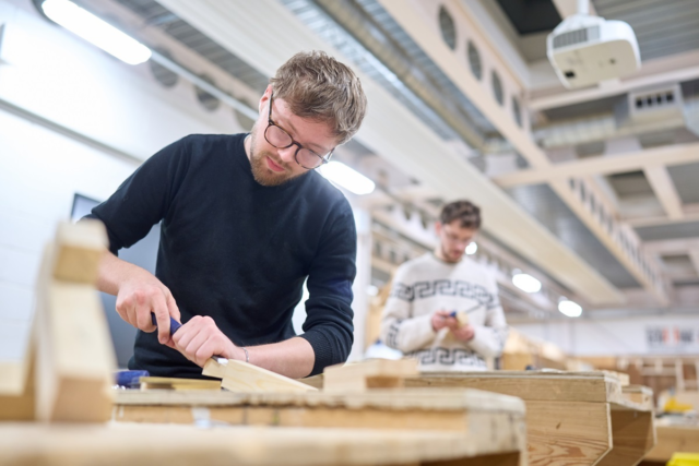 A student chisels some wood Joinery