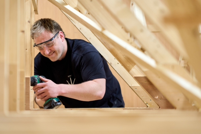 A student drills a wooden roof Joinery
