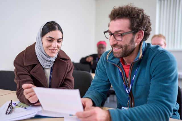 Two students smile and work through a problem GCSE Maths
