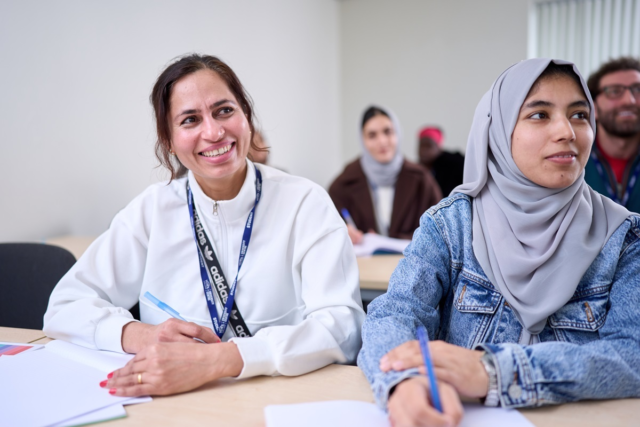 Two students smile at their tutor GCSE Maths
