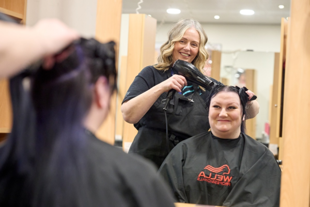 A student dries a clients hair Hairdressing
