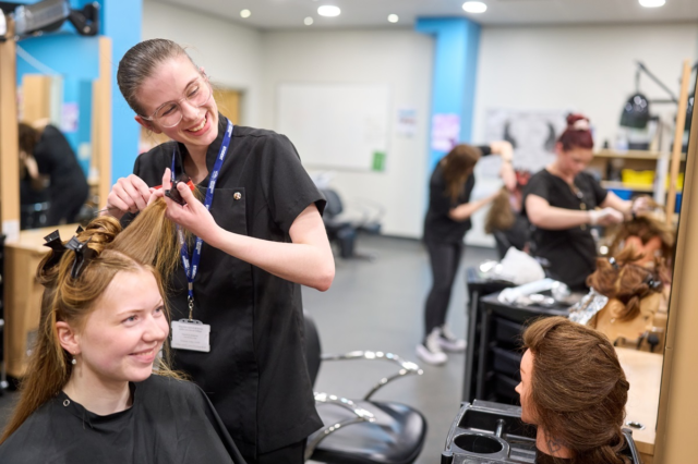 A student sections a clients hair Hairdressing