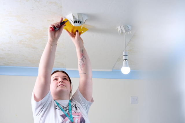 Female painting and decorating student papering the ceiling