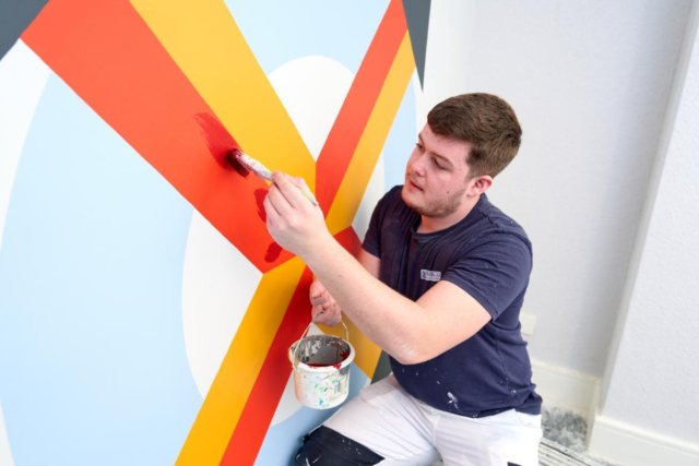 Student painting design on wall