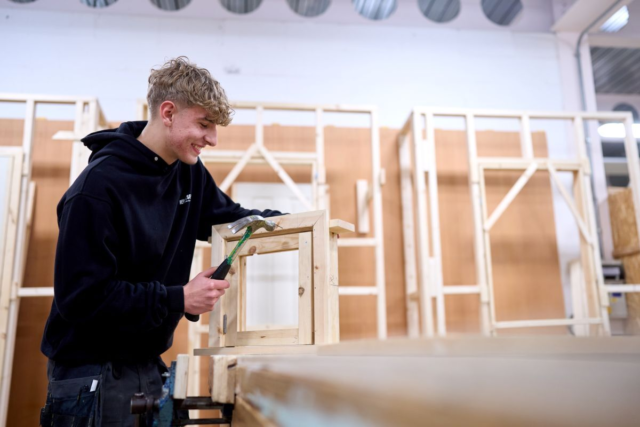 A male carpentry joinery student drilling some wood