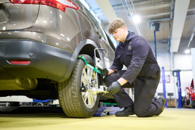 A vocational motor vehicle student is working on a car in the workshop