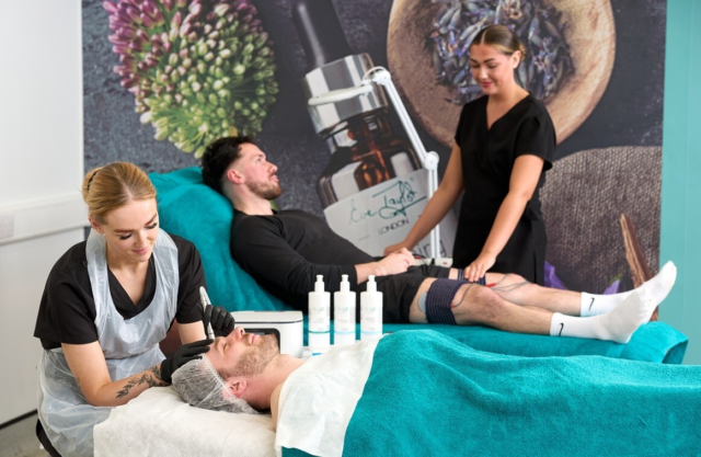 A beauty student performs a facial electrotherapy treatment and behind is a student doing an body electrotherapy treatment on a client