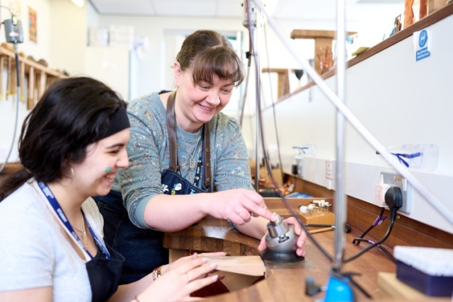 A tutor helps her student craft some jewllery Jewellery