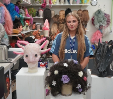 Abi Horton stood behind her media make up work on plinths including an axolotl a wig and a horses head