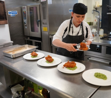 Valentina Zarins plates up battered fish on top of a bed of mushy peas in York Colleges The Cookery kitchen