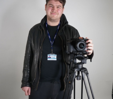 Sam Matten poses with camera on tripod