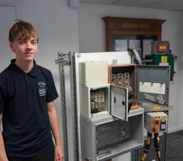 Jackson Hall stands next to an electrical engineering training unit in AGH Engineerings office